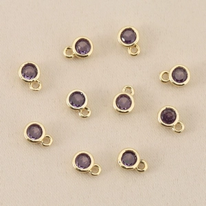 Makroaufnahme von zehn violetten Zirkonia-Anhängern mit 18k vergoldetem Rahmen für DIY-Schmuck
