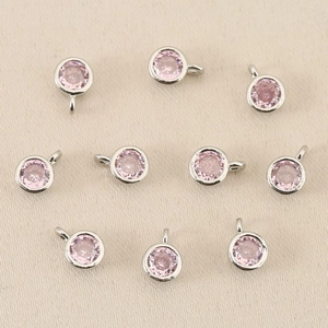 Dettaglio ravvicinato di 10 ciondoli tondi in argento con pietre rosa sfaccettate