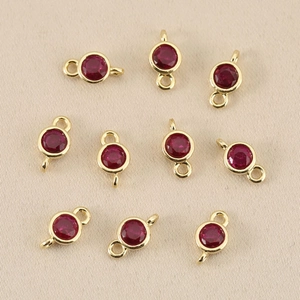 Detailed macro view of 10 round red gemstone charms with 18k gold-plated double jump rings