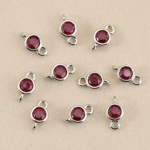Macro detail of 18k gold plated birthstone connector with vibrant red crystal stones