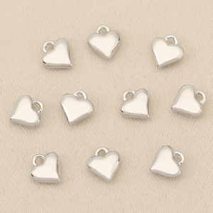 Detailed view of ten heart-shaped silver metal pendants for DIY jewelry making