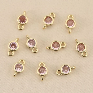Macro shot of 18k gold-plated double-loop pendants with pink faceted birthstones for DIY jewelry