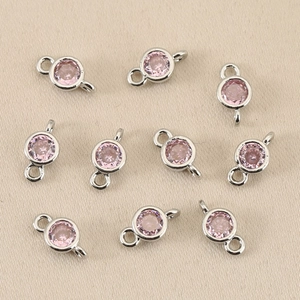 Detail of pink birthstone connectors with double rings and silver-plated metal bases