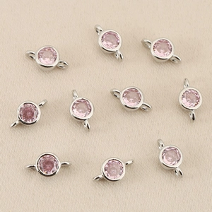 Macro detail of round pink zircon charms with 18k gold plated double loop connectors