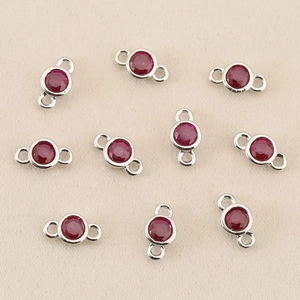 Close-up of circular red zircon charm with silver connector for DIY jewelry making