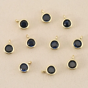 Dettaglio di dieci ciondoli tondi placcati in oro con cristalli sfaccettati blu profondo