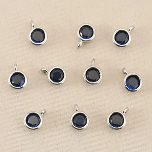 Dettaglio macro di ciondoli con pietre natali blu scuro e montatura circolare in metallo argento