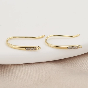 Macro shot of 18K gold-plated U-shaped ear hooks with inlaid stones on silk background