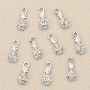 Close-up of small silver-plated pineapple charms with sparkling zircon stones