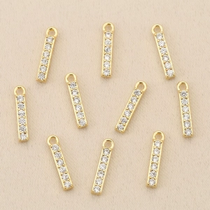 Detail of nine 18k gold plated brass pendants with sparkling cubic zirconia for DIY jewelry