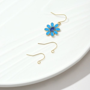 Detalle de ganchos para pendientes bañados en oro 18k con dije de margarita de esmalte azul