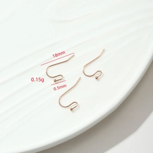 Tres ganchos de cobre oro rosa de 18mm para pendientes DIY en un plato de cerámica