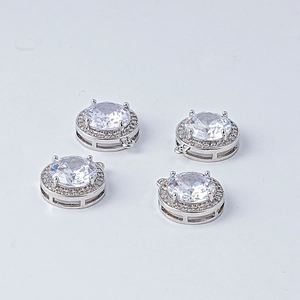 Détail macro de 4 breloques rondes argentées avec pavé de zircons pour création de bijoux