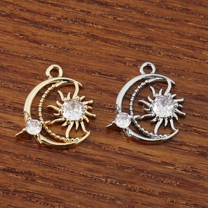 Detailed view of sun and moon pendants with cubic zirconia inlay on wood surface