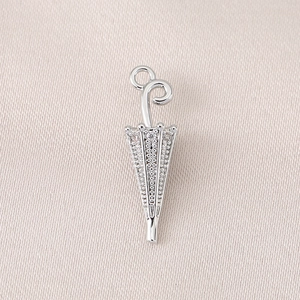 Macro detail of a 3D silver umbrella pendant with micro-pave cubic zirconia inlay