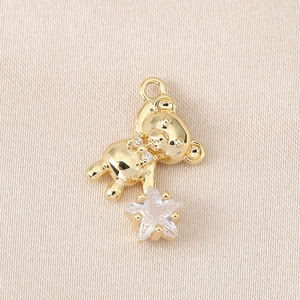 Détail d'un pendentif ours doré avec nœud en cristal et zircon en forme d'étoile