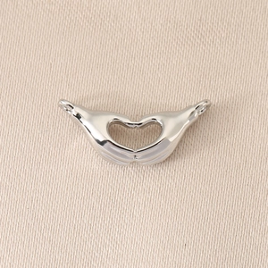 Close-up of heart-shaped hands pendant in polished silver finish for DIY jewelry