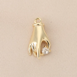 Detailed view of hand-shaped gold pendant with a sparkling heart-shaped zircon stone