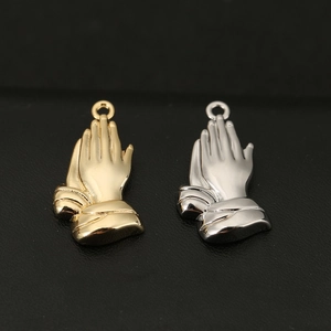 Detailed view of copper praying hands pendants in 18K gold and silver polished finishes