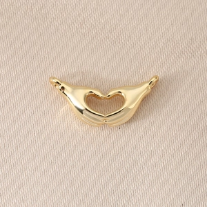 Detailed macro of 18K gold-plated heart hand gesture pendant with connector rings