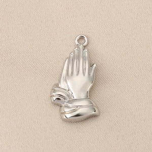 Detailed macro view of polished silver praying hands pendant with hammered texture details
