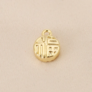 Macro detail of 18K gold-plated round pendant with embossed Fu character for DIY jewelry