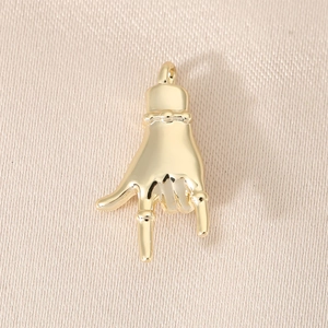 Macro shot of a 18K gold hand gesture pendant on beige textured fabric detail