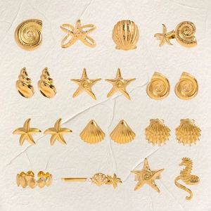 Set de joyas doradas tema océano con estrella de mar y conchas sobre piedra blanca