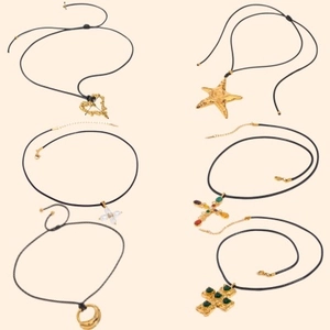 Collection of black cord necklaces with gold pendants including heart, starfish and crosses