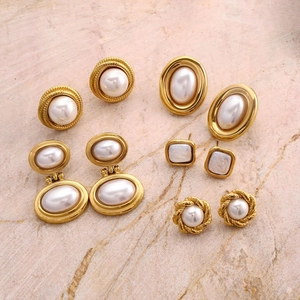 Dettaglio del set di orecchini vintage dorati con perle su base di marmo rosa