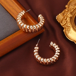 Vintage goldene gedrehte Spiral-Ohrringe in C-Form auf elegantem Seidenhintergrund