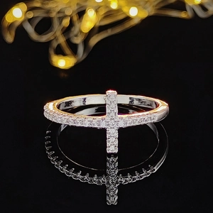 Bague croix argentée élégante avec cristaux étincelants sur une surface noire