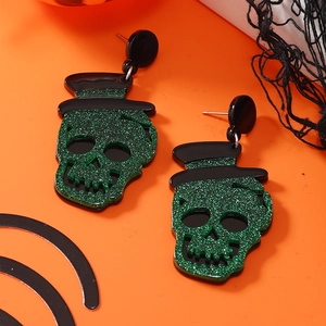 Glinsterende groene schedel oorbellen met zwarte hoeden op oranje Halloween-achtergrond