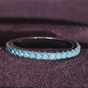 Detailed macro view of slim silver band ring featuring micro-pave light blue zircons