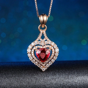 Détail du collier cœur en or rose avec pierre rouge et pavé sur une chaîne vénitienne