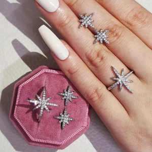 Detailed view of silver star jewelry set with zircon on hand and in pink velvet box