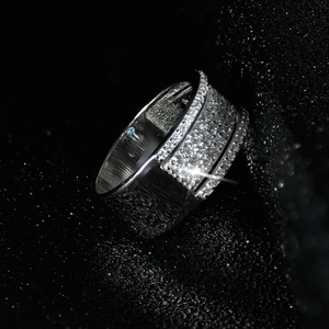 Macro de un anillo ancho plateado con pavé de circonitas 3A sobre fondo de cielo estrellado
