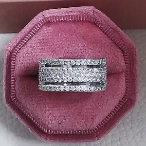 Vista superior de anillo ancho plateado con cuatro filas de circonitas en caja rosa