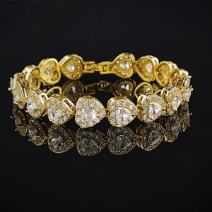 Golden heart tennis bracelet with colorful zircon crystals on a black reflective background