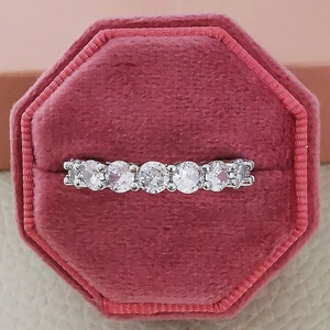 Close-up of five round-cut zircons set in a silver ring within a pink velvet box