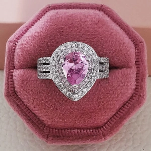 Macro shot of luxury pear-cut pink gemstone ring in velvet box with double halo detail