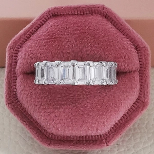 Macro shot of emerald cut zircon eternity band in a pink velvet octagon jewelry box
