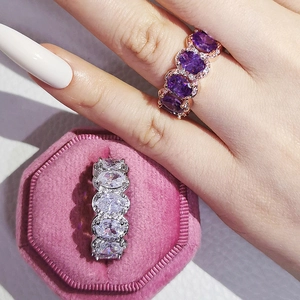 Close-up of sparkling oval-cut purple and white zircon rings in a pink velvet box