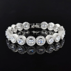 Elegant silver zircon tennis bracelet with oval stones and halo design on black surface