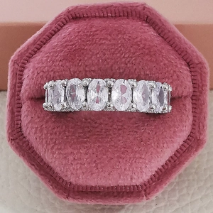 Macro shot of silver ring with seven oval-cut zircons in a pink velvet jewelry box