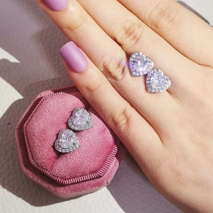 Detalle de pendientes de botón de corazón con circón en estuche de terciopelo rosa