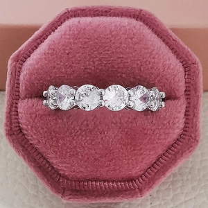Detailed macro view of silver five-stone crystal ring in a pink hexagonal velvet gift box
