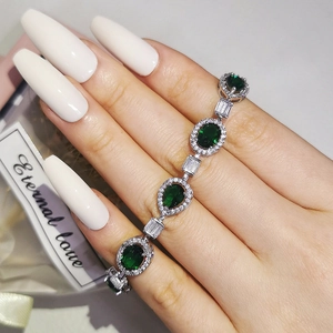 Elegant emerald bracelet with oval and teardrop stones in a silver setting worn on wrist