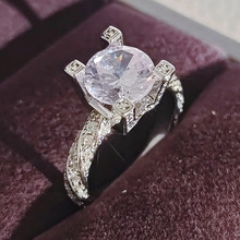 Primer plano de anillo trenzado con un diamante redondo en engaste de cuatro garras