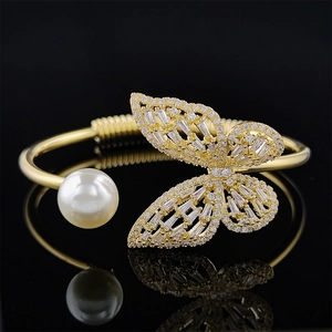 Gold open bracelet featuring a large white pearl and a zircon-encrusted butterfly